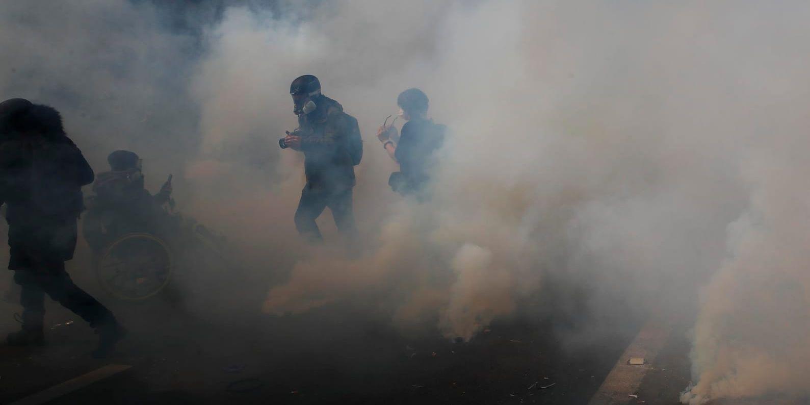 Aktivister flydde från tårgas under en förstamajdemonstration i Paris.