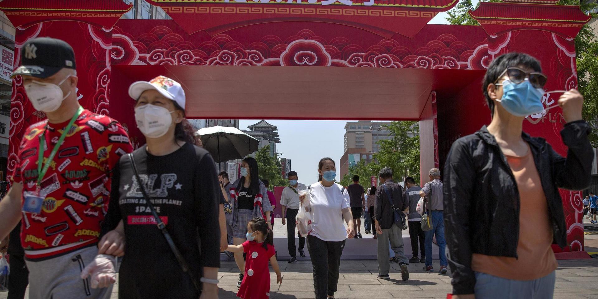 People wearing face masks to protect against the new coronavirus walk at a government event aiming to stimulate consumer demand and consumption in Beijing, Saturday, June 6, 2020. China&apos;s capital is lowering its emergency response level to the second-lowest starting Saturday for the coronavirus pandemic. That will lift most restrictions on people traveling to Beijing from Wuhan and surrounding Hubei province, where the virus first appeared late last year. (AP Photo/Mark Schiefelbein)  XMAS108